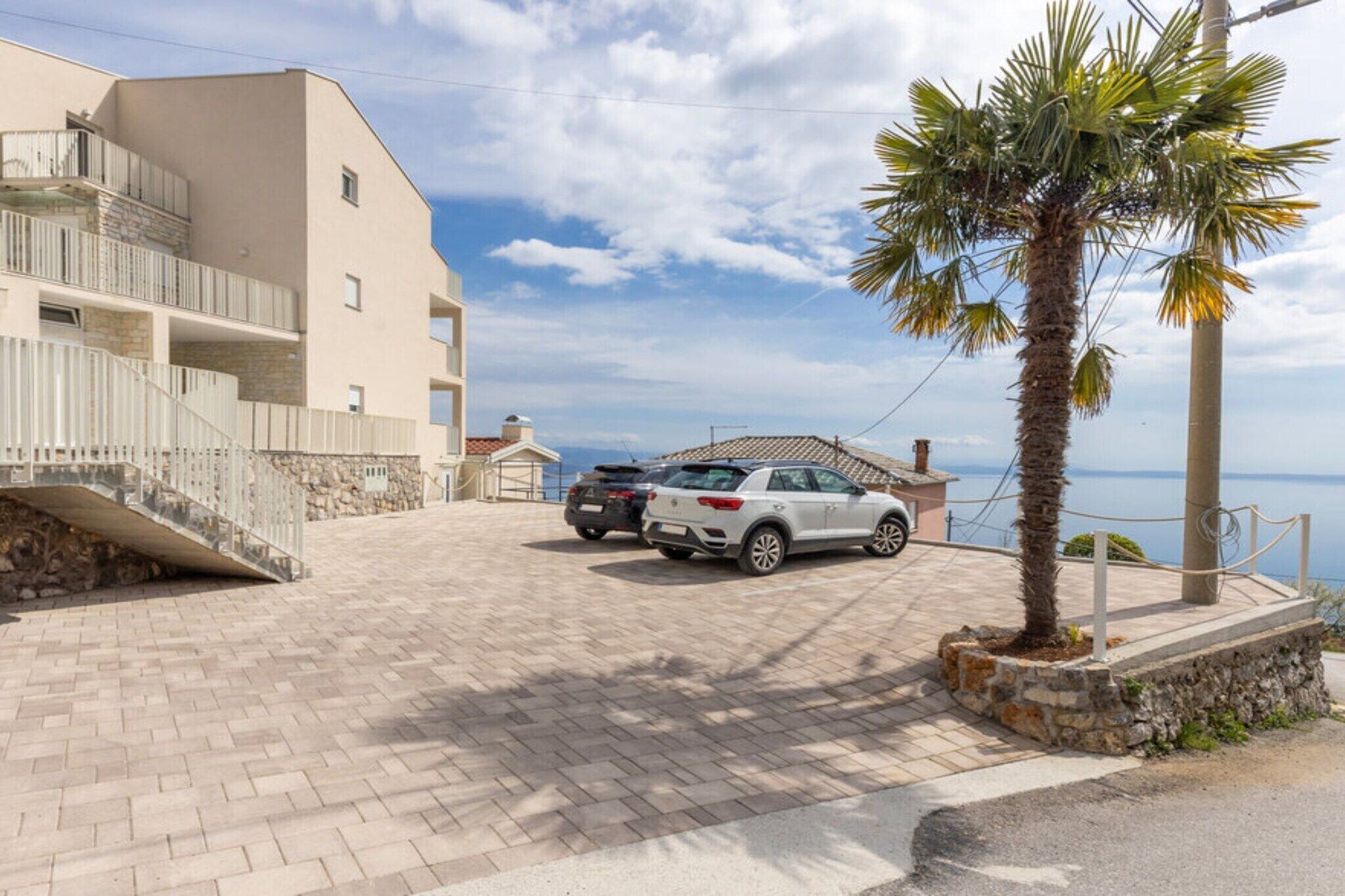 Un camino pavimentado que conduce a un edificio con una escalera de piedra y una palmera.