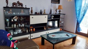 A living room with a glass coffee table, wicker furniture, and a cabinet with decorative items. - Holiday Home Marina - Two Bedroom Holiday Home with Terrace (Starigrad)
