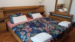 A neatly made bed with floral bedding, a bedside table with a lamp, and a mirror on the wall. - Holiday Home Marina - Two Bedroom Holiday Home with Terrace (Starigrad)
