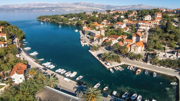 Une ville côtière dotée d’un port de plaisance, de bateaux et de bâtiments aux toits recouverts de tuiles rouges.