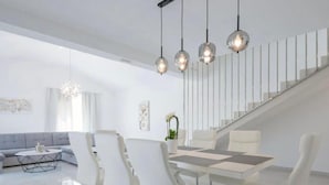 Un salon moderne avec un coin repas, un escalier et un lustre.