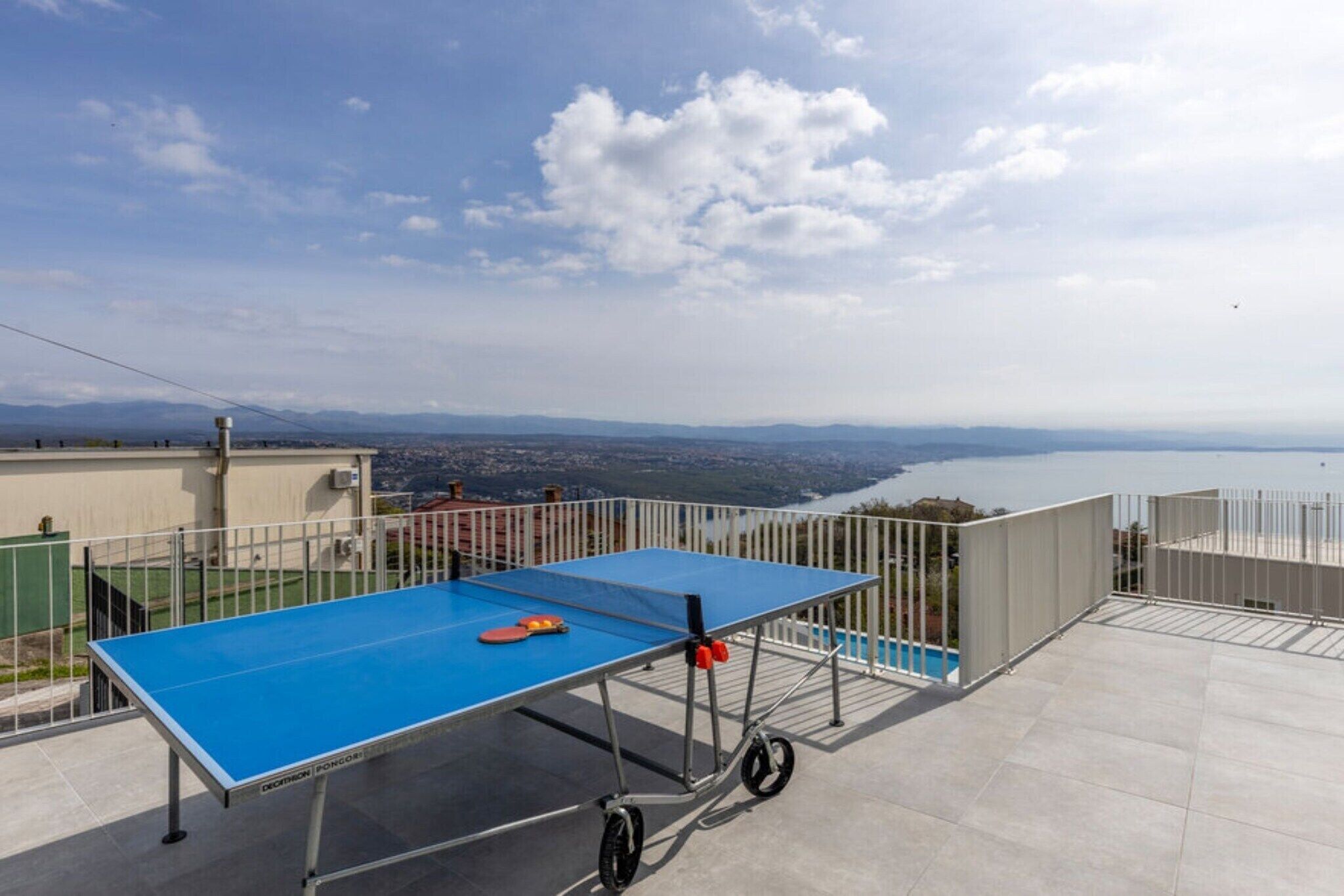 A ping pong table on a balcony with a city view.