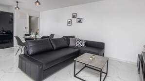 A modern living room with a black leather sofa, a small coffee table, and pendant lighting. - Apartments Bregha - One Bedrom Apartment with Terrace (Matulji)