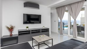 A modern living room with a flat-screen TV, grey sofa, and a small coffee table. - Apartments Bregha - One Bedrom Apartment with Terrace (Matulji)