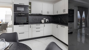A modern kitchen with white cabinets, black countertops, and a marble backsplash. - Apartments Bregha - One Bedrom Apartment with Terrace (Matulji)