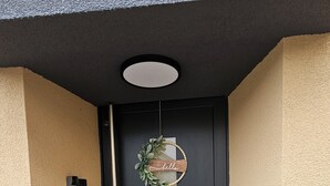 A black door with a 'hello' sign and a wreath.