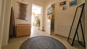 Un pasillo con un rugado decorativo, un banco tejido y una obra de arte colgando en la pared.