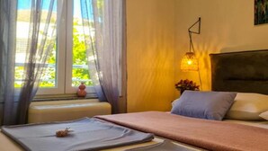 Una habitación de hotel con una cama, una mesita de noche, una lámpara y un ventanal con cortinas.