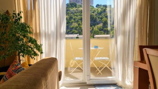 Una habitación con puerta corrediza de vidrio que da a un balcón con mesa y sillas.