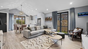 Un salon moderne avec un canapé gris, une table basse et un coin repas comprenant une table et des chaises.