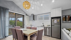 Une cuisine moderne avec un coin repas, de grandes fenêtres et une vue sur l’extérieur.