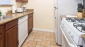 Una cocina con armarios de madera, lavavajillas, estufa y refrigerador.