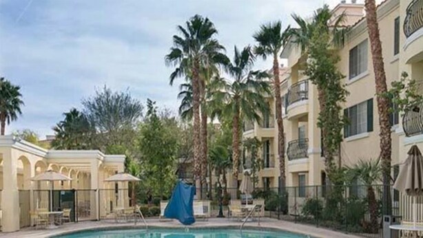 Una piscina rodeada de palmeras y un edificio con balcones.