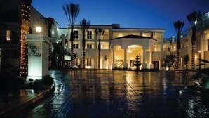 Un hotel con un patio amplio, varias entradas y una fachada bien iluminada.