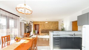 A modern kitchen with dark cabinets, a marble countertop, and a stone backsplash.