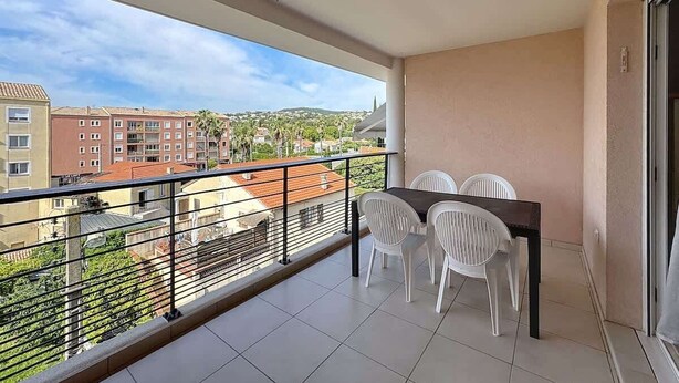 A balcony with a table and chairs, a view of buildings, and a railing. - apartment near the beach (Fréjus)