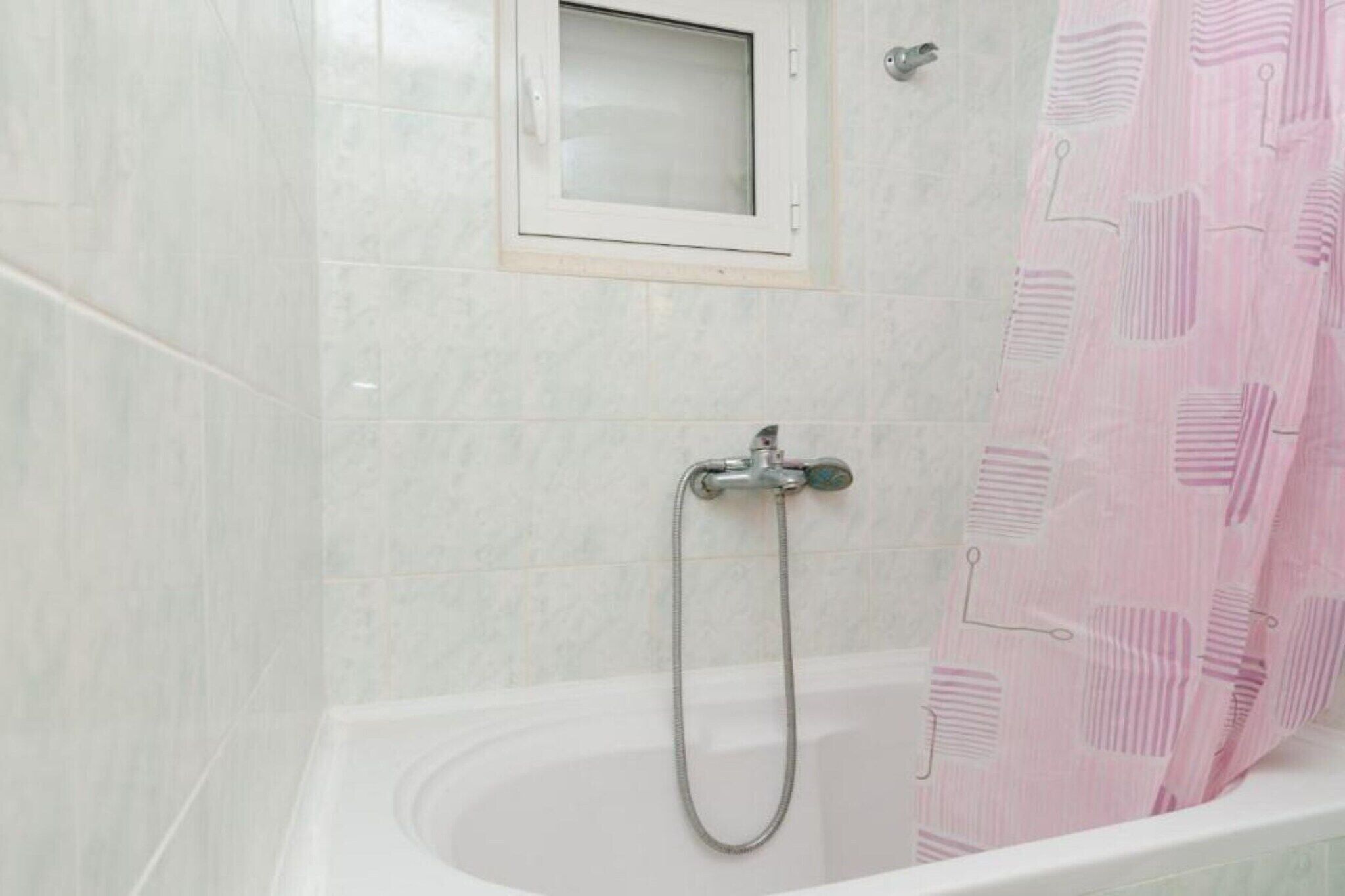 Ein Badezimmer mit Dusche, Fenster und einem rosa Duschvorhang.