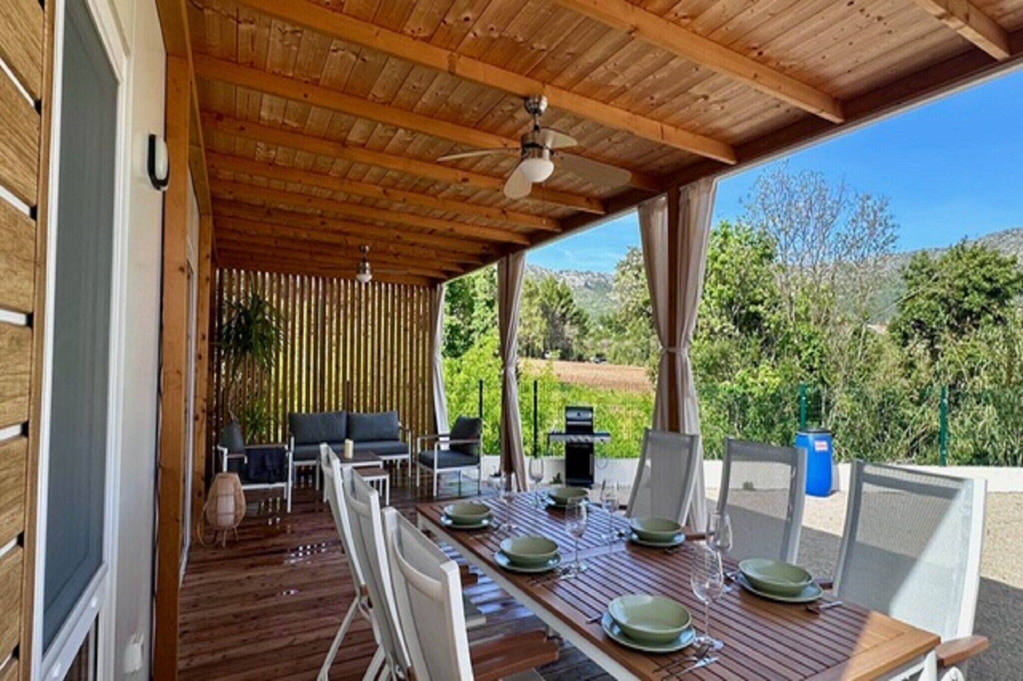 Ein Essbereich im Freien mit einer Holzterrasse, einem überdachten Bereich und Blick auf die umliegende Landschaft.