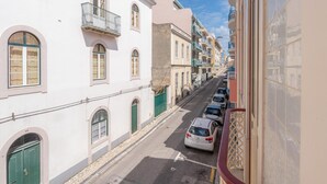 A narrow street lined with multi-story buildings, featuring balconies and arched windows.