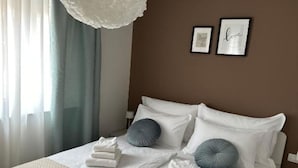 A neatly made bed with white linens and two gray pillows, a framed picture with the word "love" on the wall, and a white ceiling light. - One Bedroom Apartment with Balcony and City View (Zadar)