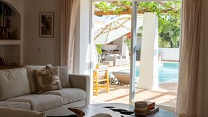 Ein Wohnzimmer mit einer Couch, einem Couchtisch und Blick auf eine Terrassenanlage mit Pool.