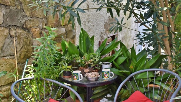Een klein terras met een tafel, stoelen en plantenpotten.