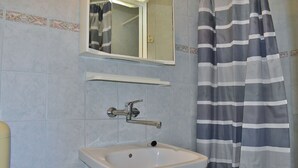 Een badkamer met een witte wastafel, een spiegel en een douchegordijn met strepen.