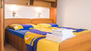 Ein Bett mit einer gelb-blauen Bettdecke, zwei Wandleuchten und einem hölzernen Kopfteil.