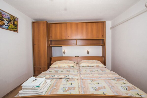 Une chambre à coucher avec un lit en bois, deux tables de chevet, une armoire en bois et un tableau accroché au mur.