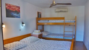 A bunk bed room with a ceiling fan, an air conditioner, and a painting on the wall. - Apartments Jug - Comfort Studio Apartment with Balcony and Sea View (Lopar)