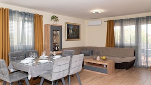A modern living room with a dining table, grey upholstered chairs, a sofa, and a coffee table.