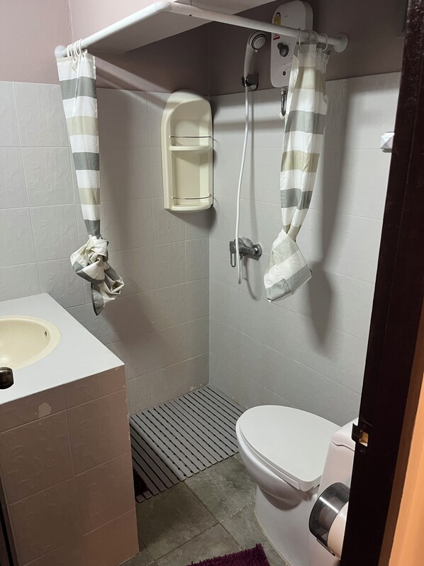 A small bathroom with a toilet, a sink, a shower, and a towel rack. - PINK HOUSE (Koh Samui)