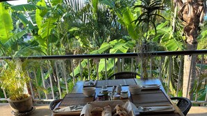 A dining table set outdoors with food, condiments, and a potted plant. - PINK HOUSE (Koh Samui)