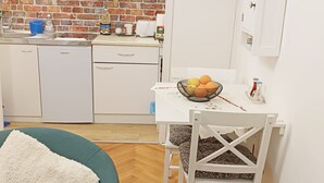 A compact kitchen with white cabinets, a sink, and a dining area with a table set for two. - Charming Apartment with Terrace and Old Town View - One Bedroom Apartment with Terrace (Dubrovnik)