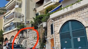 A multi-story building with balconies, stone walls, and a large green door. - Charming Apartment with Terrace and Old Town View - One Bedroom Apartment with Terrace (Dubrovnik)