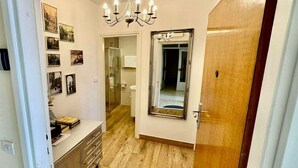 A hallway with a wooden floor, a mirror, and a door. There are pictures on the wall and a chandelier above. - Charming Apartment with Terrace and Old Town View - One Bedroom Apartment with Terrace (Dubrovnik)