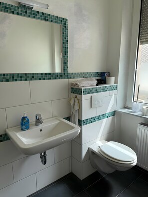 A bathroom with a white sink, a mirror, a toilet, and a window. - Apartment 'Neunkirchen City' with Wi-Fi (Neunkirchen)