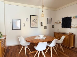 A dining area with a round wooden table, white chairs, a wooden cabinet, and framed artwork on the wall. - Apartment 'Neunkirchen City' with Wi-Fi (Neunkirchen)