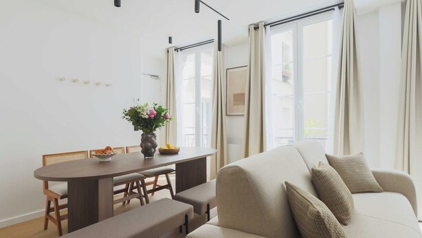A modern living room with a sofa, a dining table with chairs, and a vase of flowers. - Elegant apartment - 3BR-8P- Le Marais (Paris)