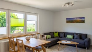 A room with a dining table, chairs, a sofa, and a painting on the wall. - Apartment 'Mit 65qm' with Private Terrace, Private Garden and Wi-Fi (Vogtsburg)
