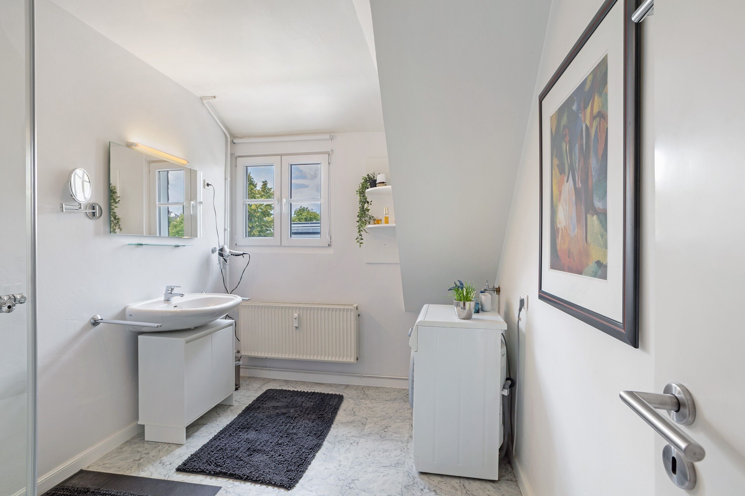 A modern bathroom with a sink, mirror, and radiator.