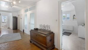 Un passadís amb un armari de fusta, un radiador i un altre radiador blanc en una habitació amb parets blanques i terres de fusta.