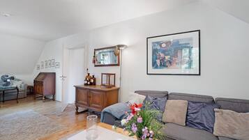 A living room with a grey sofa, a wooden cabinet, a mirror, and a framed picture on the wall.