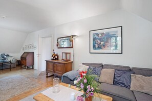 A living room with a grey sofa, a wooden cabinet, a mirror, and a framed picture on the wall.