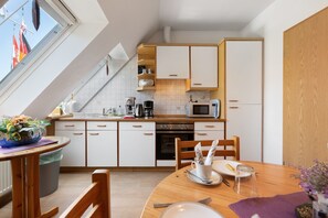 A modern kitchen with white cabinets, a microwave, and a dining area with a table set for two.