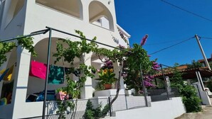 Un bâtiment blanc doté de fenêtres en arc de cercle et de balcons, entouré de verdure et de fleurs.