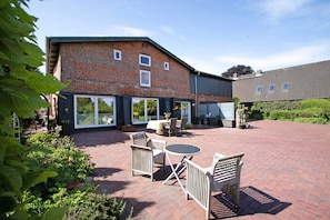 A courtyard with a brick building, outdoor seating, and greenery. - Holiday Home 'Alte Tischlerei' with Private Terrace, Shared Garden and Wi-Fi (Hemmingstedt)