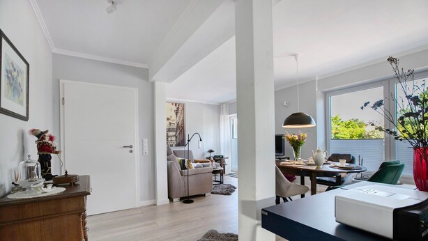 Ett modernt vardagsrum med en soffa, ett soffbord och en matplats med ett bord och stolar.