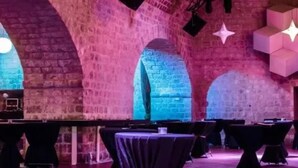 An interior with arched brick walls, tables with black tablecloths, and star-shaped light fixtures.