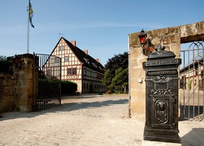 A traditional half-timbered building with a stone gate and a street lamp.